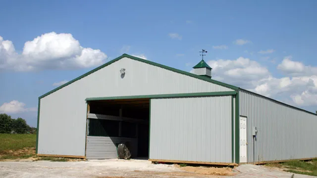 Cream barn with a green roof, two cupolas and a wide open bay