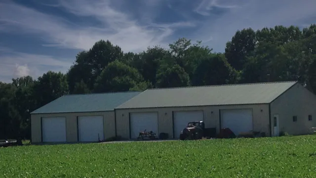 Long cream machine shed with a green roof and a row of overhead doors