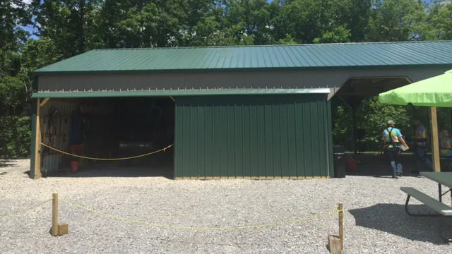 Green open-front machine shed with a green roof on a gravel pad