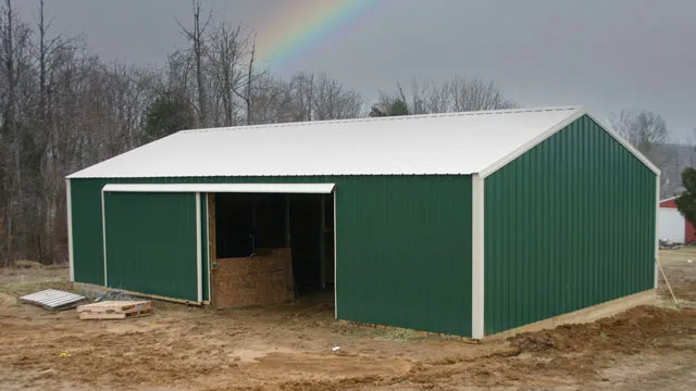 Green barn with a white roof and an open bay with hay stored inside