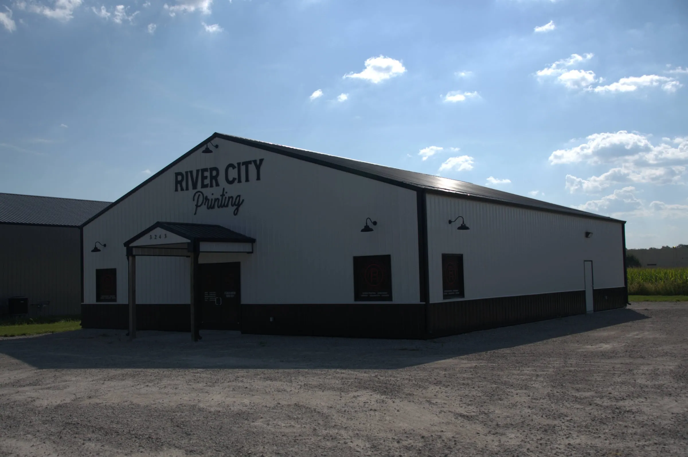 Dark commercial building with a gable-end entry porch, wall lights and a painted business sign