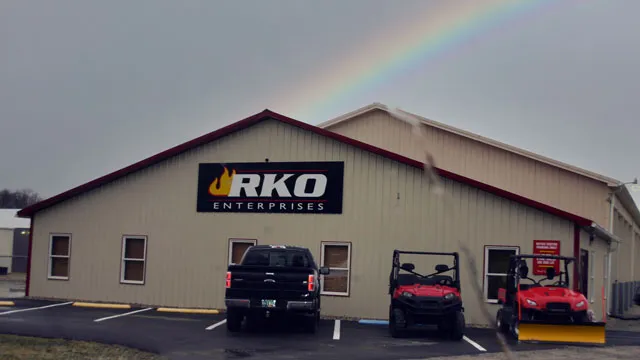 Tan commercial building with signage and windows, vehicles parked on the lot