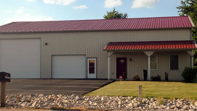 Tan commercial building with a red roof, an overhead door, an entry canopy and landscaping