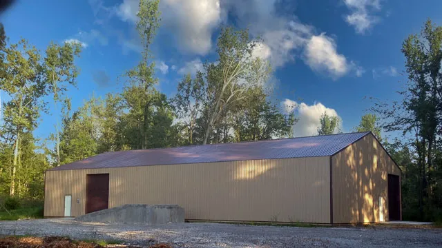 Tan commercial building with a brown roof and an overhead door on a gravel lot