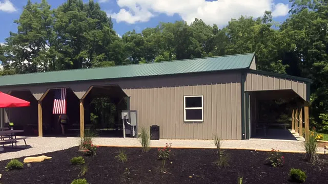 Tan commercial building with a green roof and a long timber-post covered porch