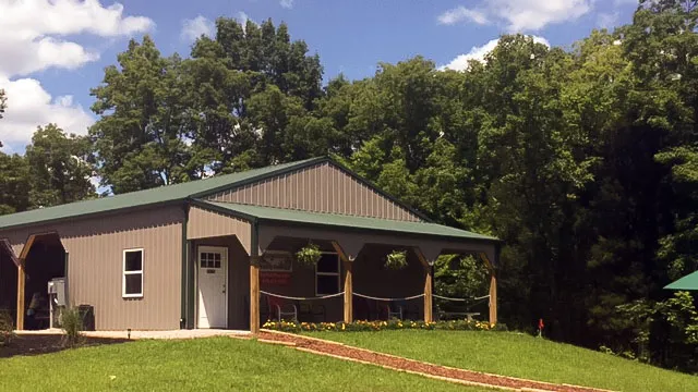 Tan building with a green roof, a covered porch and a walkway to the door