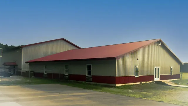 Long green commercial building with a red roof and maroon wainscot