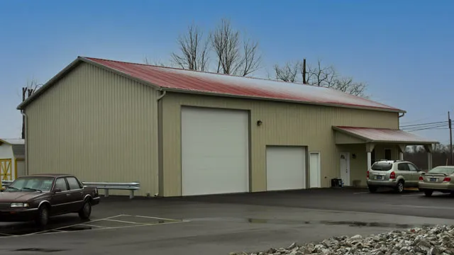 Cream commercial building with a red roof, a tall overhead door and parking