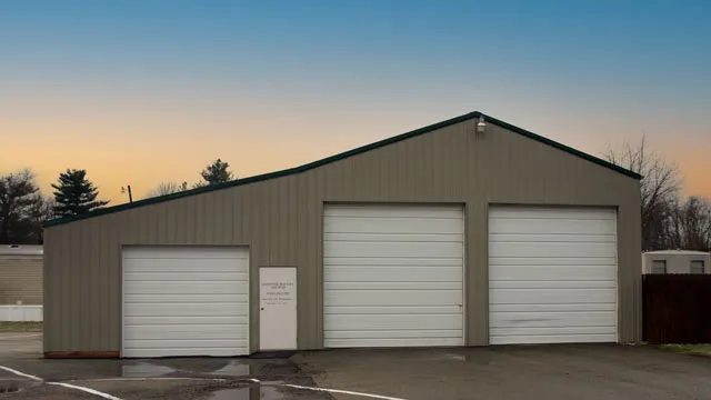 Gray commercial garage with three white overhead doors and a walk door
