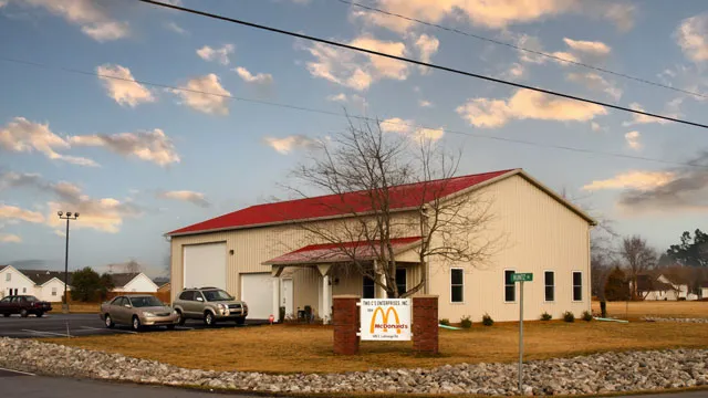 Cream building with a red roof and a sign at the road