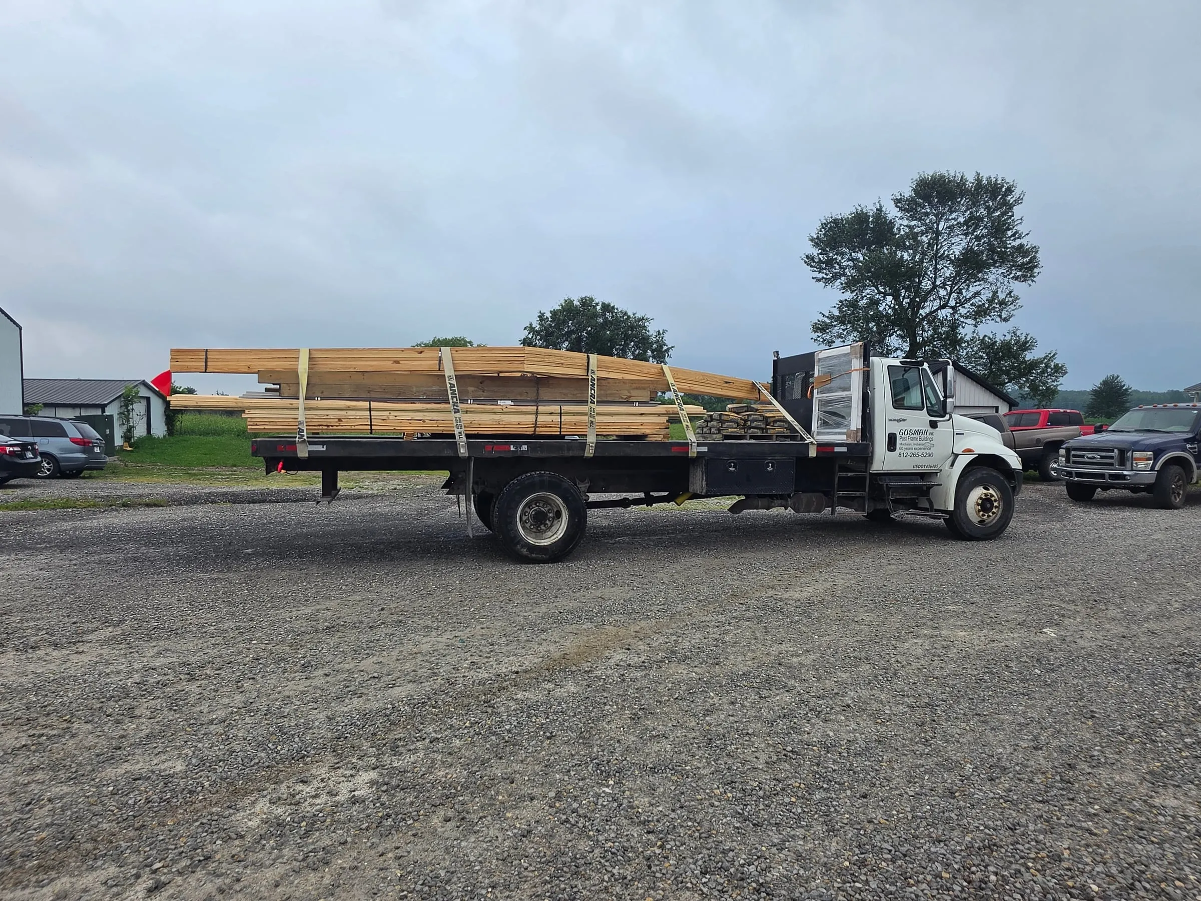 A complete building kit strapped and bundled on a Gosman flatbed truck in the yard