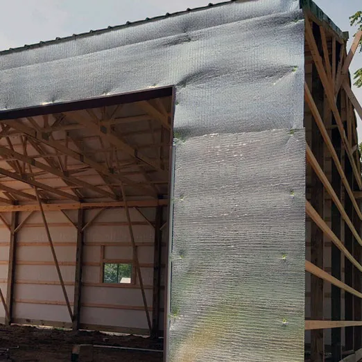 Foil-faced lining being fitted to a gable wall inside a building