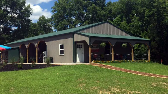 Cream building with a green roof and a wrap-around shed porch