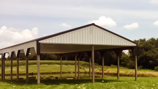 Open pole shelter with a brown roof standing over grass