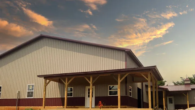 Cream building with maroon wainscot and a timber-post porch at sunset