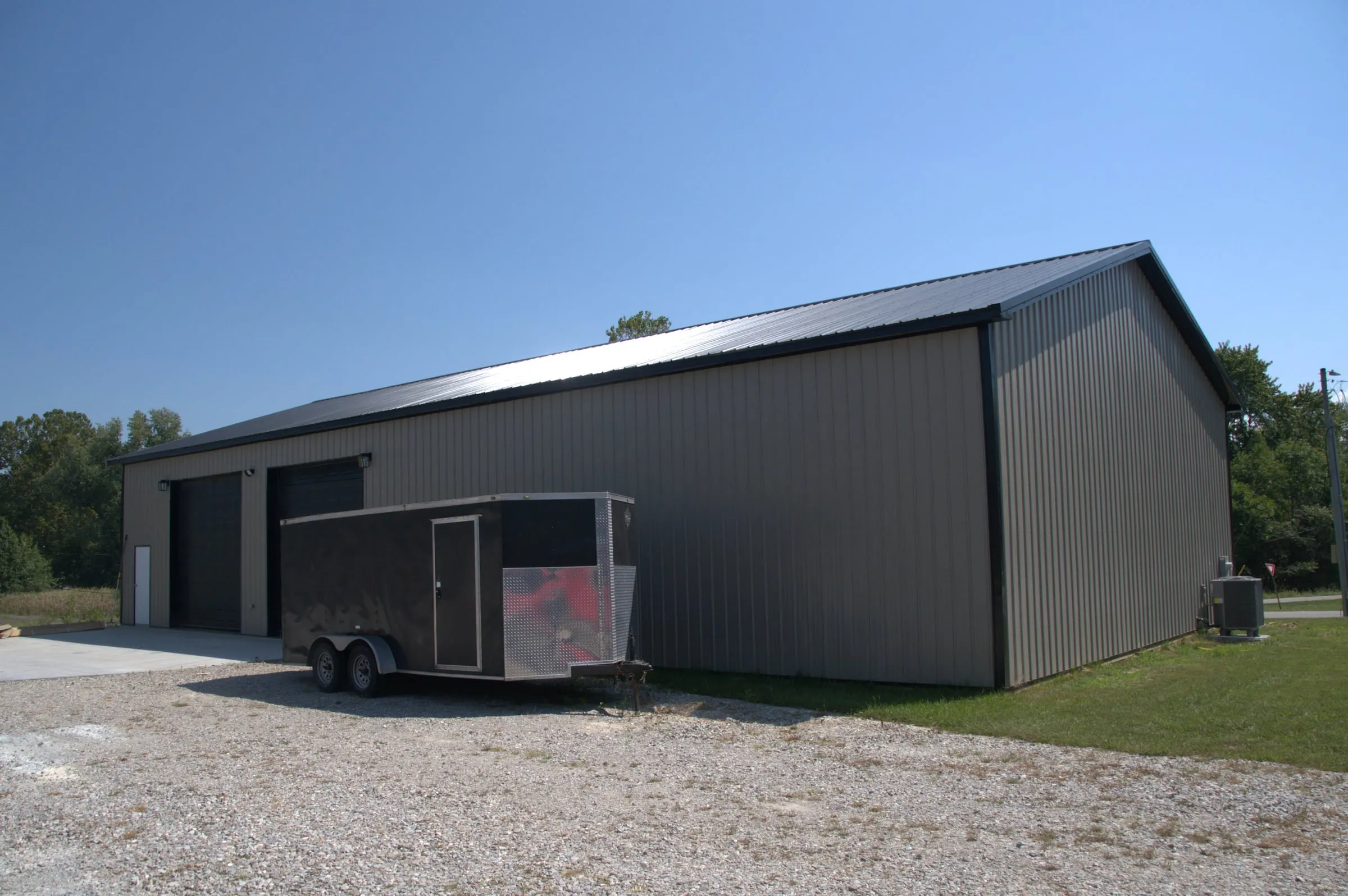 Charcoal shop with a black roof and a sliding door, an enclosed trailer parked in front