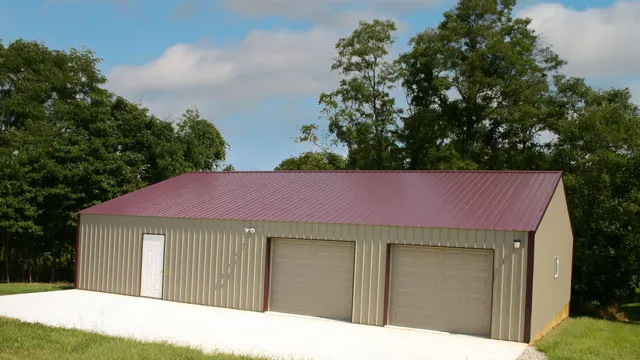 Tan shop with a red roof, two brown overhead doors and a white walk door on a concrete apron