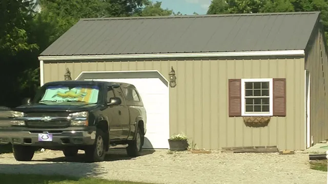 Sage green garage with a white overhead door and shuttered window, pickup parked outside
