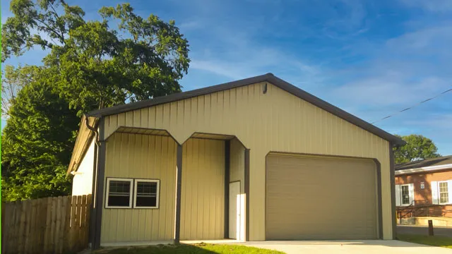 Tan shop with a wide overhead door, three windows and a walk door, house behind