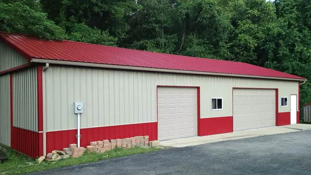 Cream shop with a red roof and red wainscot, two white overhead doors and a paved drive