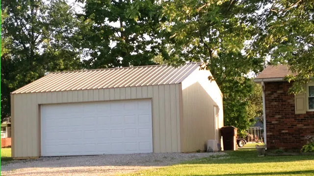 Cream garage with a tan roof and one white overhead door beside a brick house