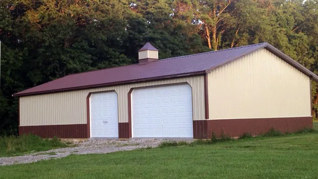 Cream shop with a maroon roof and wainscot, two white overhead doors and a cupola