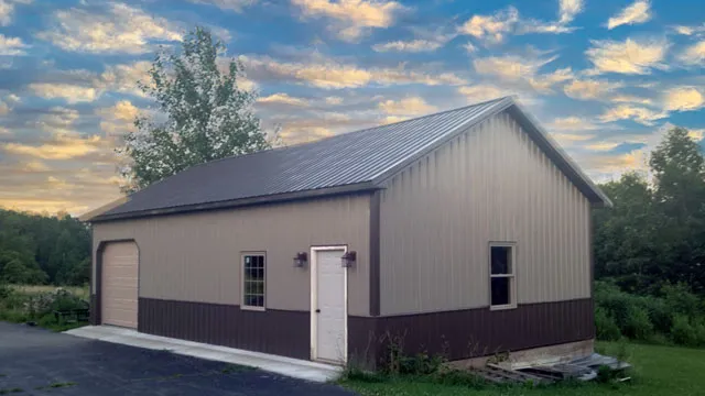 Tan shop with a brown roof and wainscot, an overhead door, a walk door and two windows