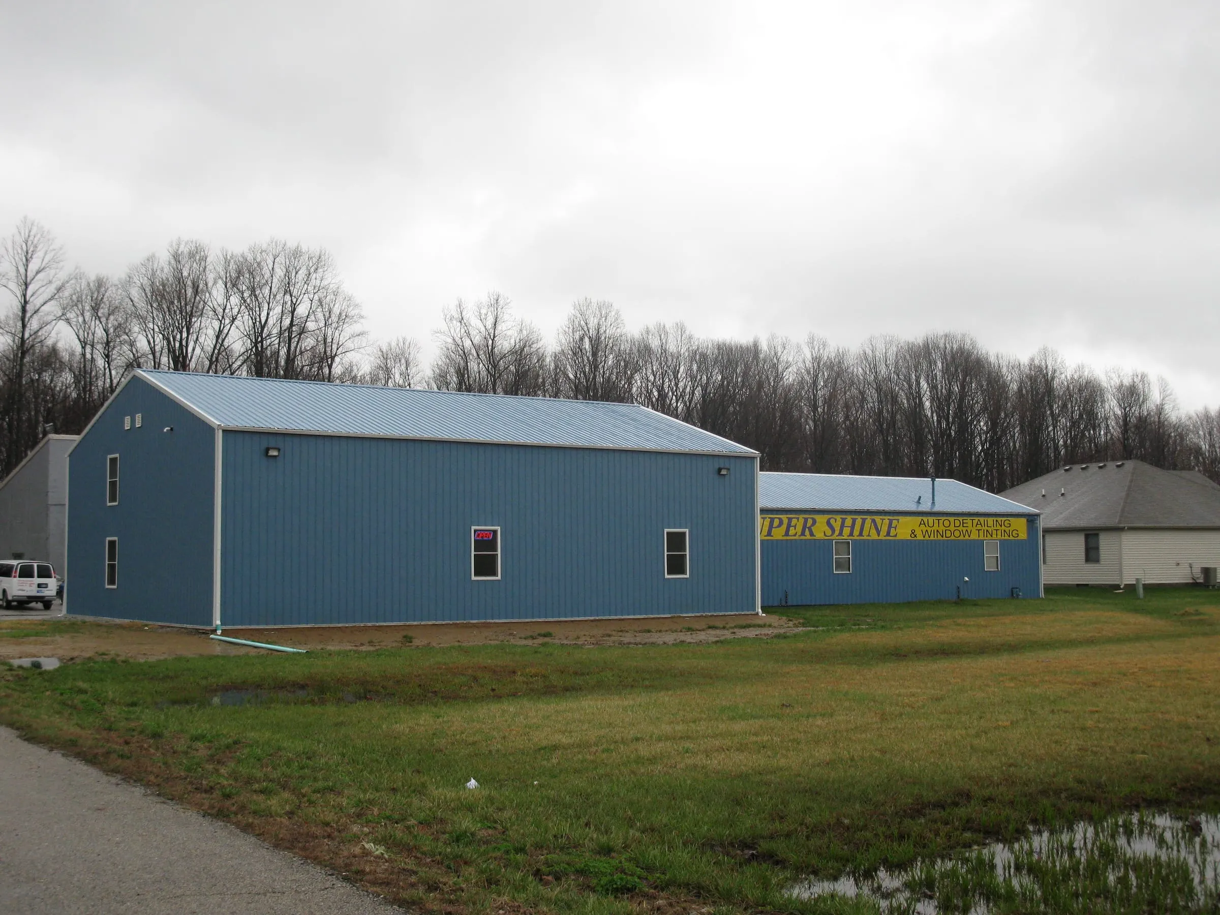 Blue building with white trim and windows beside a second blue building carrying a car wash sign