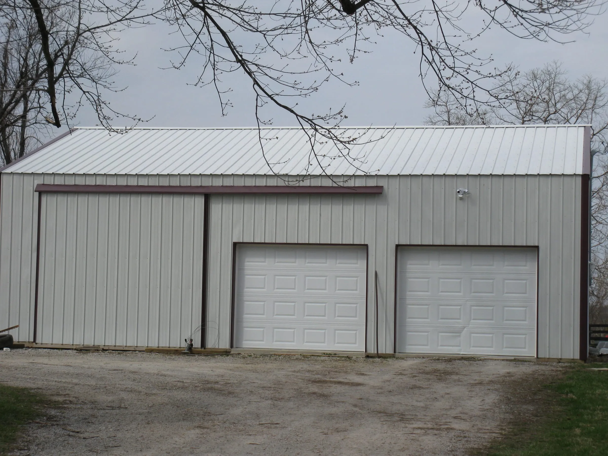 Cream building with brown trim, two white overhead doors and a sliding door at the far end