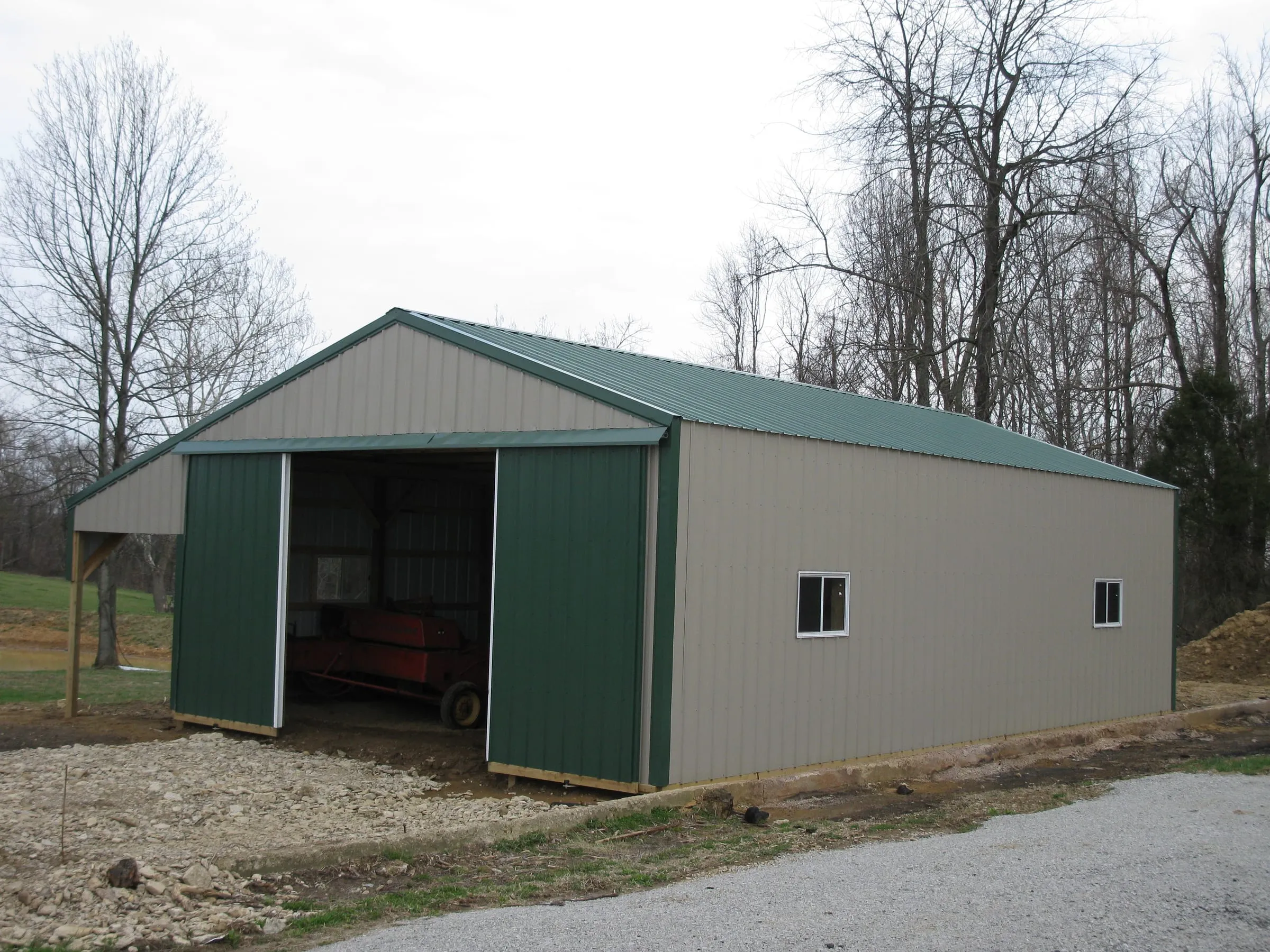 Cream barn with a green roof and an open bay with red equipment inside