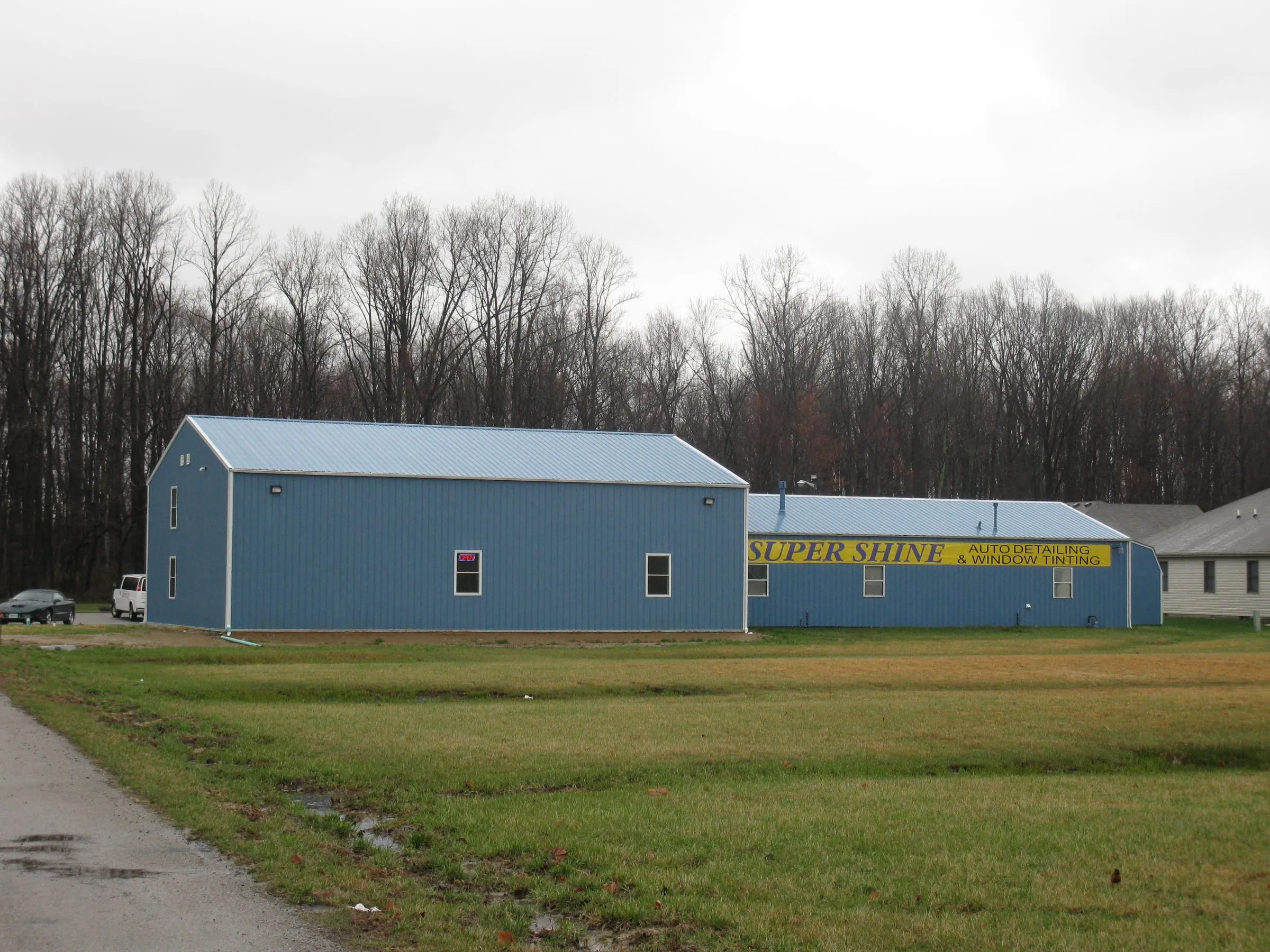 Blue commercial building with white trim and windows, car wash signage behind