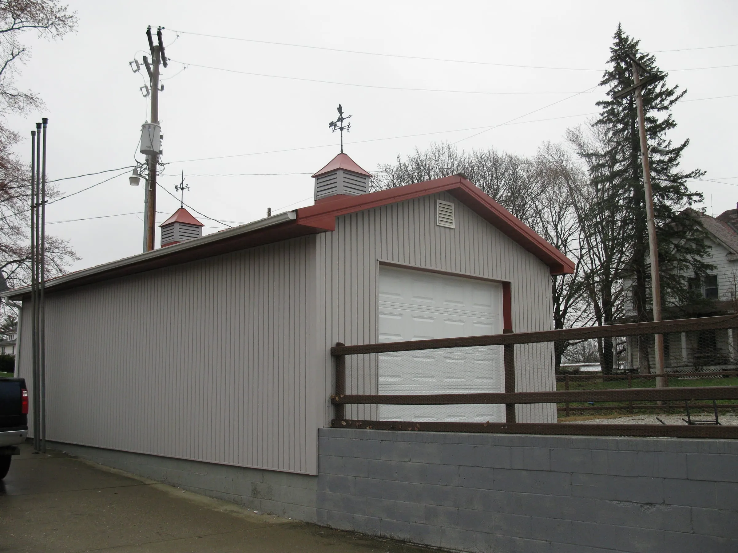 Commercial building with a red-brown roof and a white overhead door, cupolas on the ridge and a block base