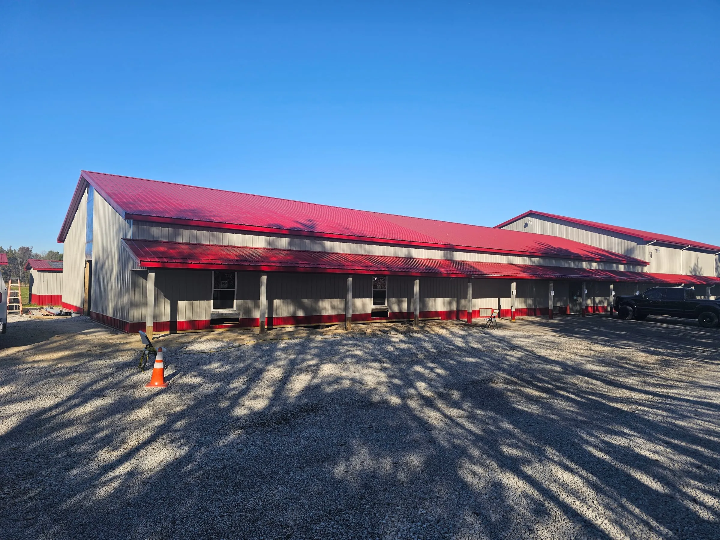Long cream building with a red roof and open bays, seen down the length of the run