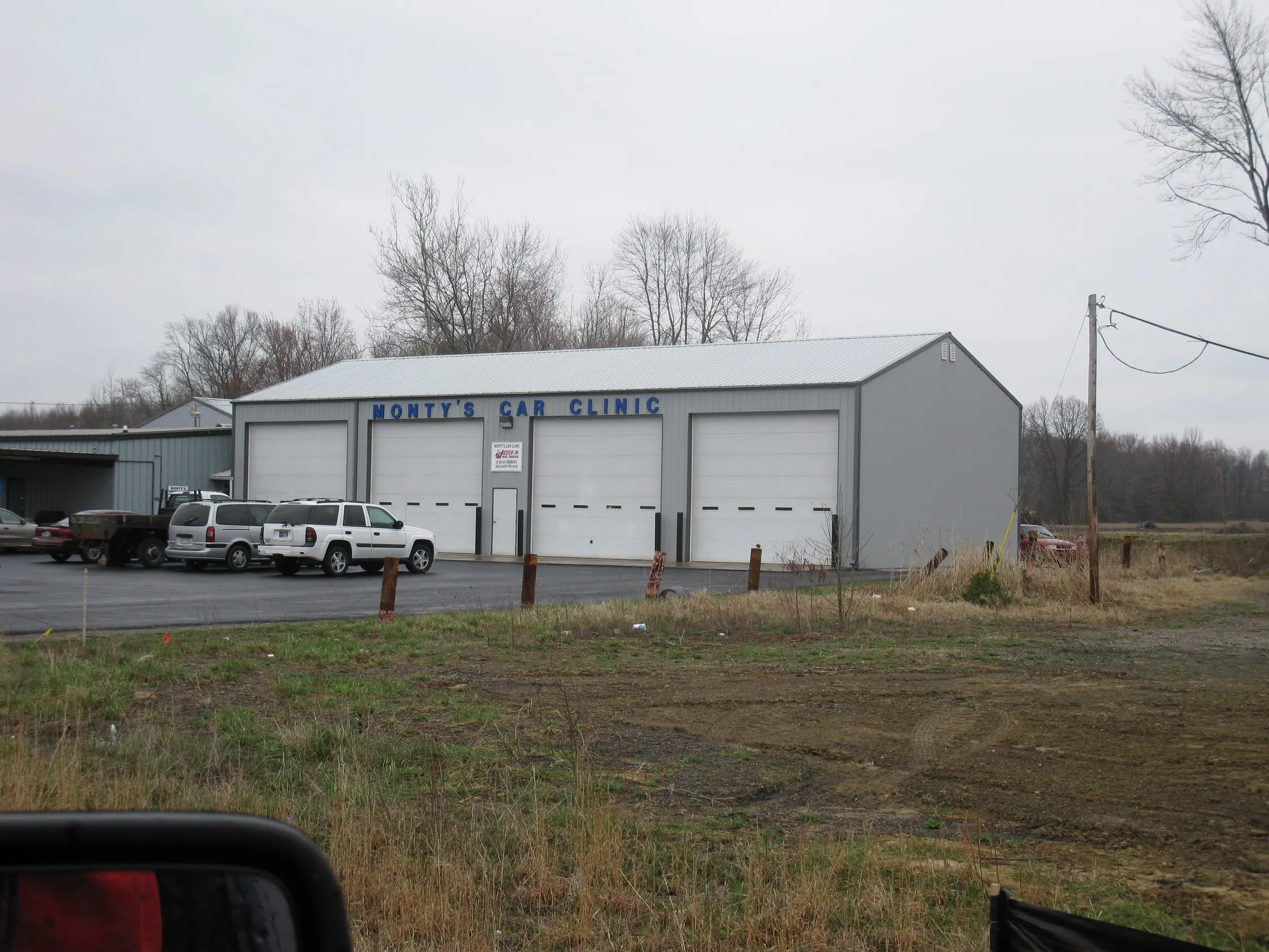 Long gray commercial building with signage and white service trucks on the lot