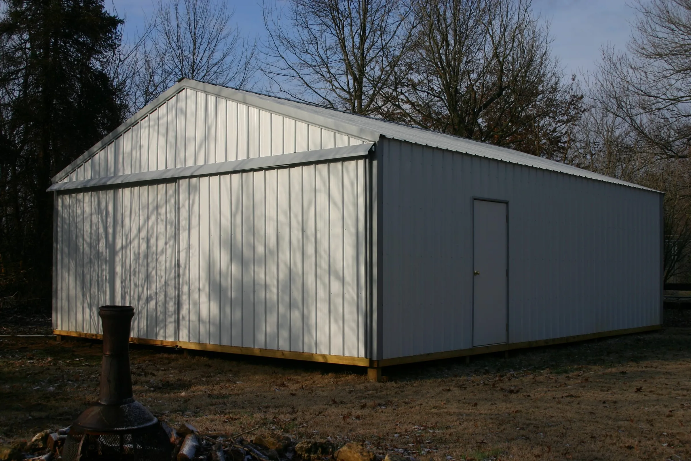 White building with gray trim and a walk door, smoker standing out front