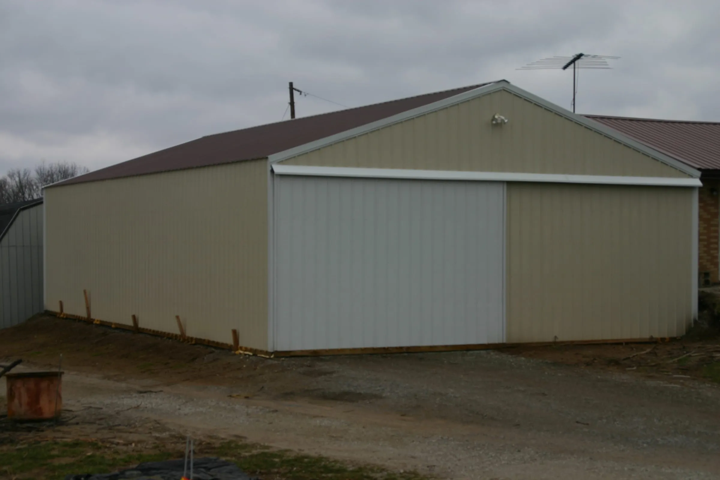 Cream building with brown trim seen from the gable end, on a gravel drive